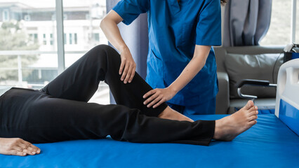 Asian female physiotherapist helping senior older woman stretching hamstring, Rehabilitation...