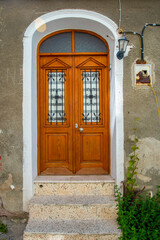 A wooden double door, with dark brown windows with a stone wall.