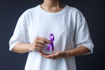 Woman holding purple ribbon. Symbol is used to raise awareness for Alzheimer's disease, elder abuse, epilepsy, pancreatic cancer, thyroid cancer and lupus. 
