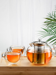 Asian tea concept, two glass cups of tea and teapot, space for a text on white background. Brewing and Drinking tea.