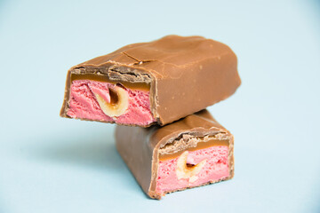 Tasty chocolate bar with whole hazelnut and strawberry on a blue background