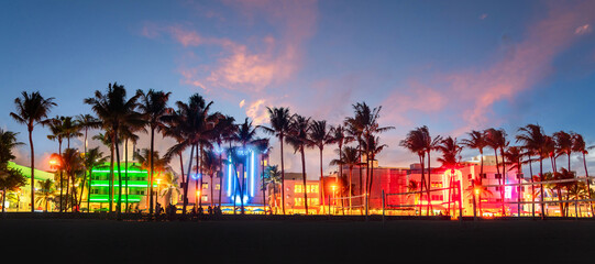 Miami Beach Ocean Drive panorama with hotels and restaurants at sunset. City skyline with palm trees at night
