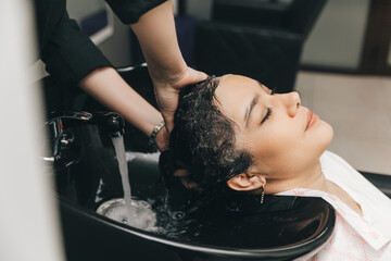 The hairdresser washes the head of a girl in a barbershop. brunette came for a haircut