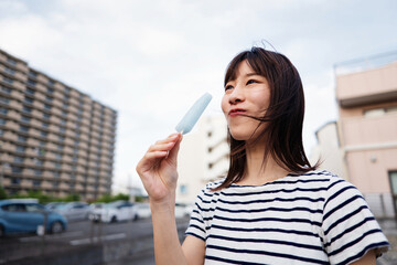 暑い夏の日に外でアイスを食べる女性