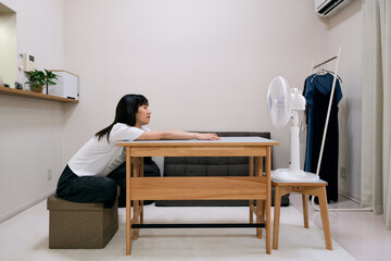 暑い夏の日に扇風機の風で涼む女性