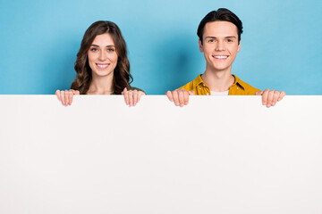 Photo of positive promoters young couple friends hold big billboard advertise new shopping center...
