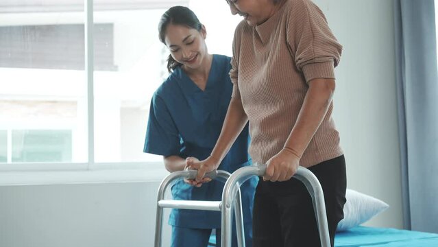Asian senior care nurses and grandmothers provide caring support to elderly women hand clasp to encourage exercising with elder disabled person patient with caregiver in nursing care.