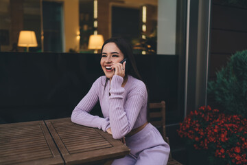 Fototapeta premium Cheerful woman talking on smartphone in cafe