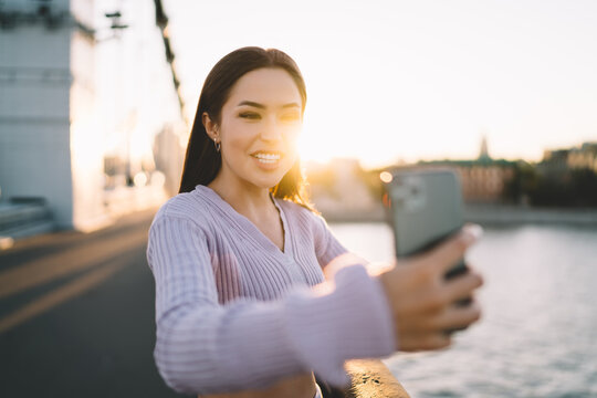 Cheerful woman making picture on cellphone on bridge