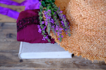 straw hat, paper book, bouquet of purple wildflowers on old wooden table, touching romantic items of nostalgia, concept education, nostalgia, knowledge