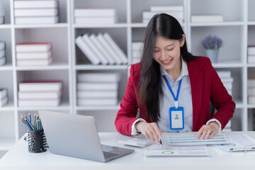 Portrait of young professional businesswoman writing on paper and use smartphone while sitting at office.