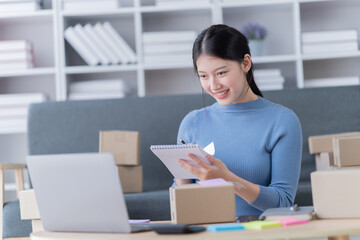 Startup SME small business entrepreneur of freelance Asian woman using a laptop with box Cheerful success Asian woman her hand lifts up online marketing packaging box and delivery SME 