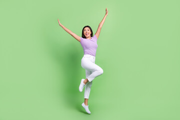 Fototapeta na wymiar Full body photo of funky attractive vietnamese woman jump dancing raised hands up crazy rhythm isolated on green color background