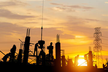 Silhouette of Engineer and worker team checking project at building site background, construction site with sunset in evening time background