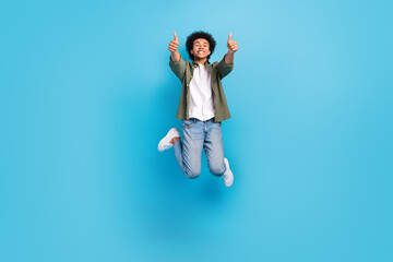 Fototapeta na wymiar Full length body photo of jumping overjoyed friendly man thumbs up wear stylish outfit positive crazy isolated on blue color background