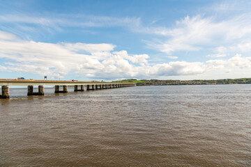 Fototapeta na wymiar road bridge over the river tay from dundee to fife in scotland shot on a sunny spring day with fluffy white clouds and blue sky