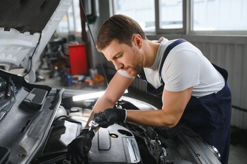 Portrait Shot of a Handsome Mechanic Working on a Vehicle in a Car Service. Modern Clean Workshop.