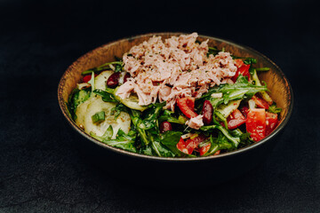 A tossed salad with tomatoes, cucumber, arugula and kindey beans and tuna