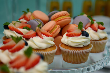 Delicious vanilla cupcakes with cream cheese, decorated with pieces of fresh strawberries and...