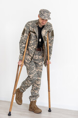 Portrait of soldier with crutches against white background