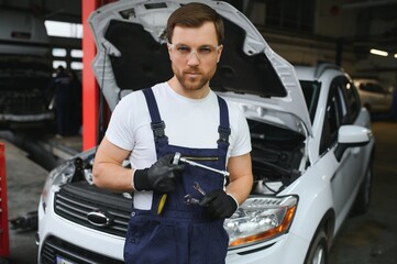 Portrait Shot of a Handsome Mechanic Working on a Vehicle in a Car Service. Modern Clean Workshop.