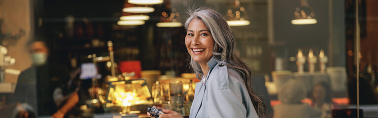 Mature woman using camera in sidewalk cafe
