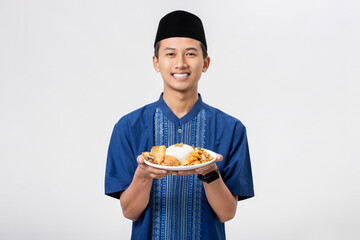 Young muslim man volunteer holding and sharing food for other person isolated on white background. Concept of alms, food sharing and help each other.