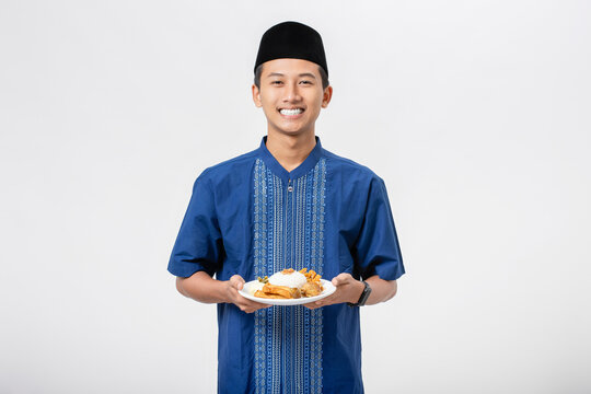 Young muslim man volunteer holding and sharing food for other person isolated on white background. Concept of alms, food sharing and help each other.