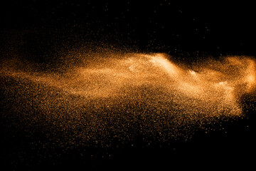 Fototapeta na wymiar orange dust particles explosion on black background. Color powder dust splash.
