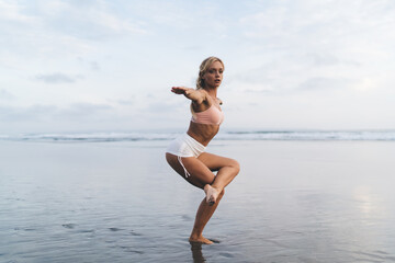 Fototapeta na wymiar Portrait of calm blonde yogi looking at camera during pilates practice warm up at seashore beach, Caucasian female enjoying healthy lifestyle and weekend for sportive exercising for mindfulness
