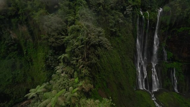 Dive rainy tropical island waterfall speed water fall stream stones rainforest mountain valley aerial view. FPV sport drone shot exotic jungle cascade fern greenery woodland cliff creek pool scenery