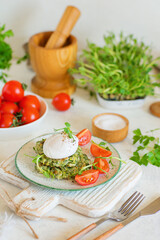 Poached egg on zucchini and greens fritters on a plate with pea microgreens and tomatoes. Blurred background