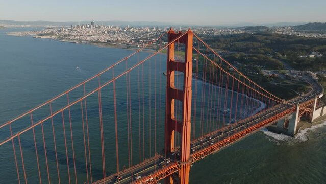 Aerial footage of tall steel bridge tower and metropolis in background. Traffic on Golden Gate Bridge. San Francisco, California, USA