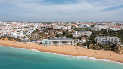 Fototapeta na wymiar Aerial photo of the beautiful town in Albufeira in Portugal showing the Praia de Albufeira golden sandy beach, with hotels and apartments in the town, taken on a summers day in the summer time.