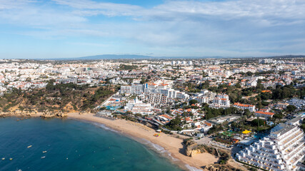 Naklejka na ściany i meble Aerial photo of the beautiful town in Albufeira in Portugal showing the Praia da Oura golden sandy beach, with hotels and apartment in the town, taken on a summers day in the summer time.