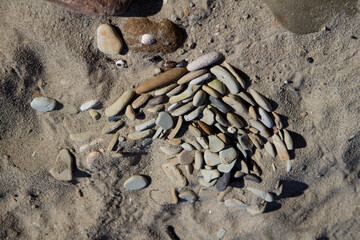 Stones on sand at beach. Sea stones background at seashore. Colored stone on coastline. Stone on sand background at sea beach.