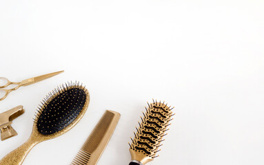 Golden hairdresser tools on a white background, scissors, comb, clip, brush. Hair salon accessories, template with space for text.