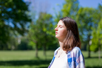 Woman relaxing and enjoying the sun in a warmth park at sunset