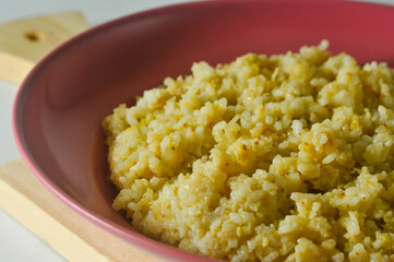 Fried rice, an Indonesian specialty, is served on a red plastic plate on a wooden board isolated on a white background
