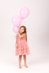 Fototapeta na wymiar Cute smiling little girl in a pink princess dress posing with air balloons isolated on white background. Kids Birthday party celebration concept. Happy Birthday banner with copy space. Studio shot.