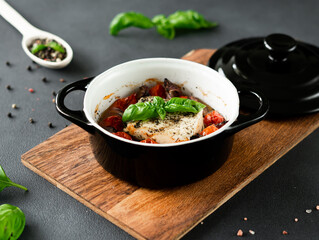 Feta cheese, blue Onions, cherry Tomatoes and Basil Baked in olive oil with spices on a black background