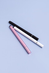 Three stylus pens for tablet on blue background. Pink, white and black stylus