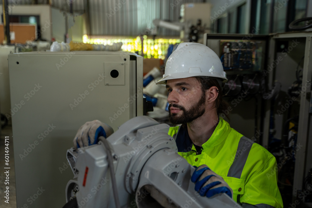 Leinwandbilder engineer and mechanic worker checking and maintain industrial robot arm controller inside the factor