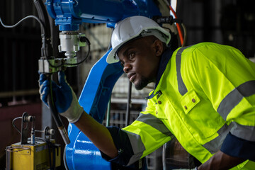 Engineer working with robot arm automated welding machine in modern metal factory.