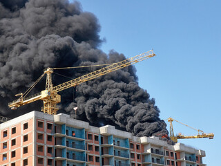 Huge clouds of smoke against the sky, a large fire at a construction site.