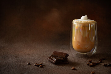Cup of cappuccino with pieces of chocolate on dark background