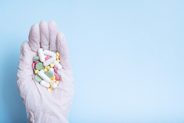 Colorful pills in gloved hand. Healthcare and medicine concept flat lay
