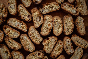 Italian biscotti with hazelnuts on wooden plate on dark brown blurred background 