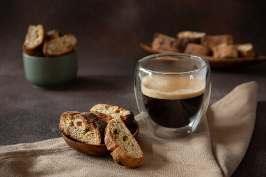Italian biscotti with hazelnuts on wooden plate on dark brown blurred background 