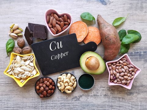 Copper high food. Natural food sources of copper with chemical symbol Cu. Assortment of fresh fruit, vegetable, nuts, seeds high in copper. Dark chocolate, avocado, spirulina, nut, seed, sweet potato.